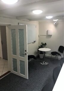 Før billede af hyggekrog i mødelokale med bord og stole
