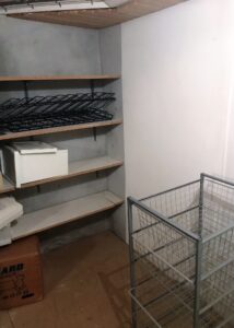 Før billede af reolvæg i opbevaringsrum i kælderen