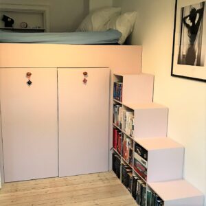 Specialbygget seng med garderoben nedenunder og opbevaring under trappen. Malet i farven powder.